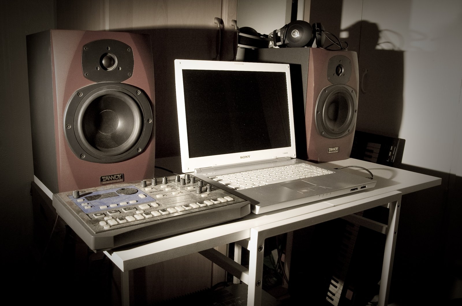 A laptop, headphones, and monitor speakers on a small home desk — the visual register of focused lo-fi work