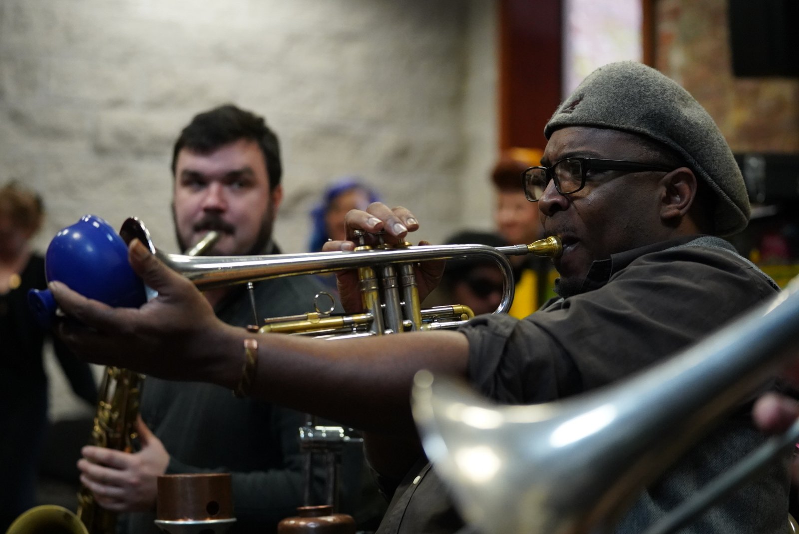 A trumpet player mid-phrase at a New Orleans jazz session — the visual register of jazz as open method
